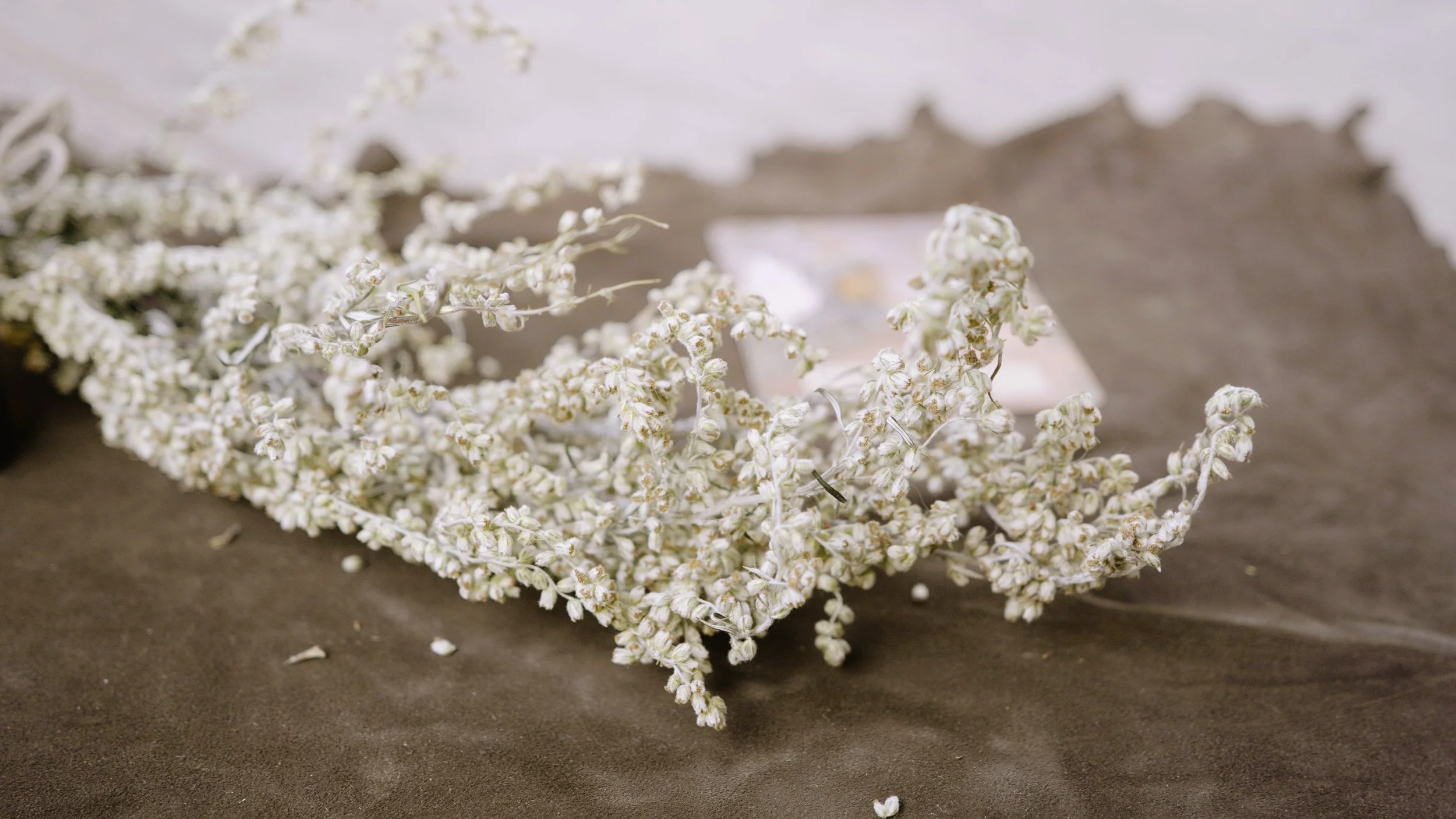 A crown made of white floral material resting on a dark surface with a blurred background.