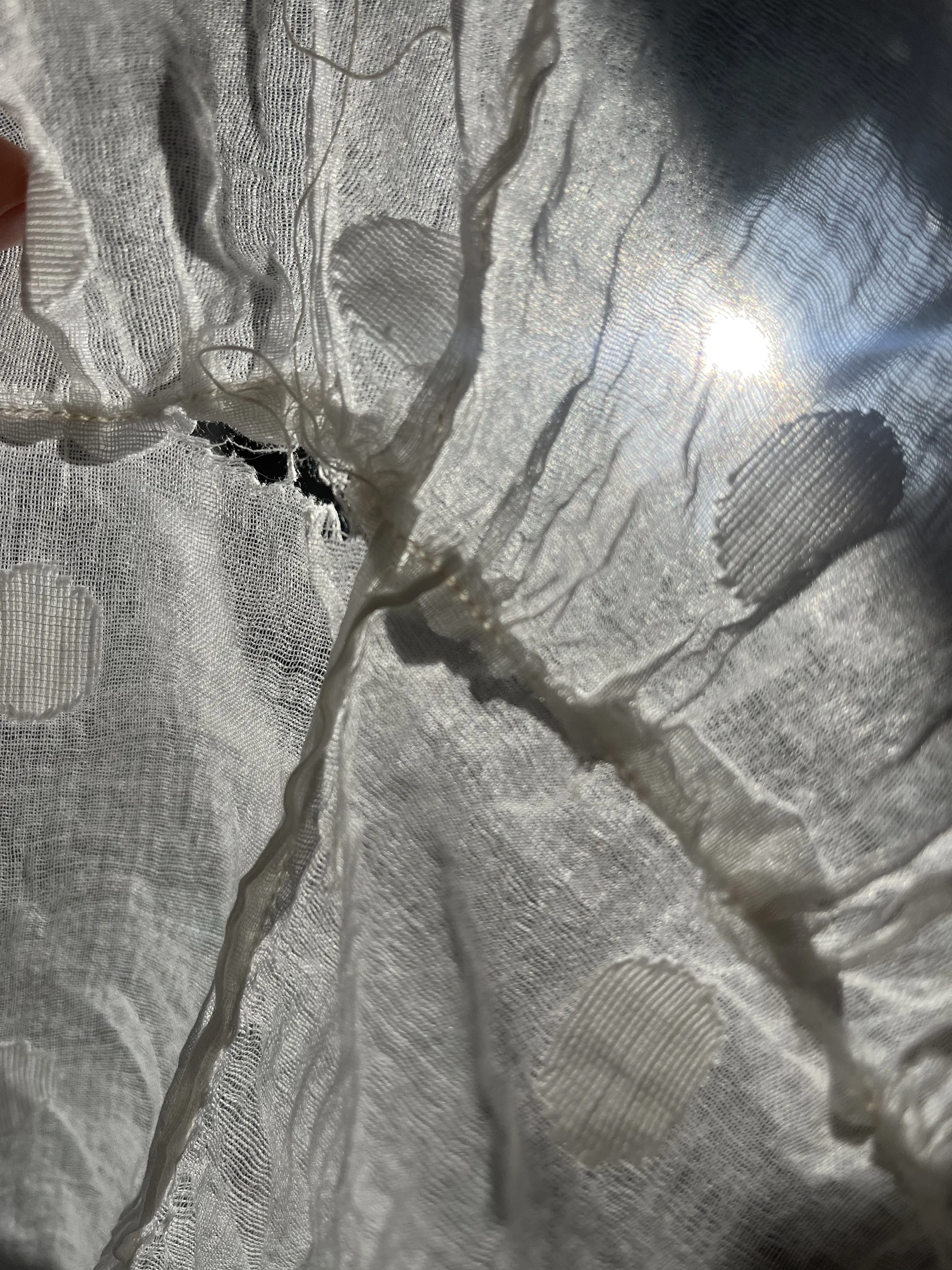 1950s wedding dress finding a hole by holding to light.webp