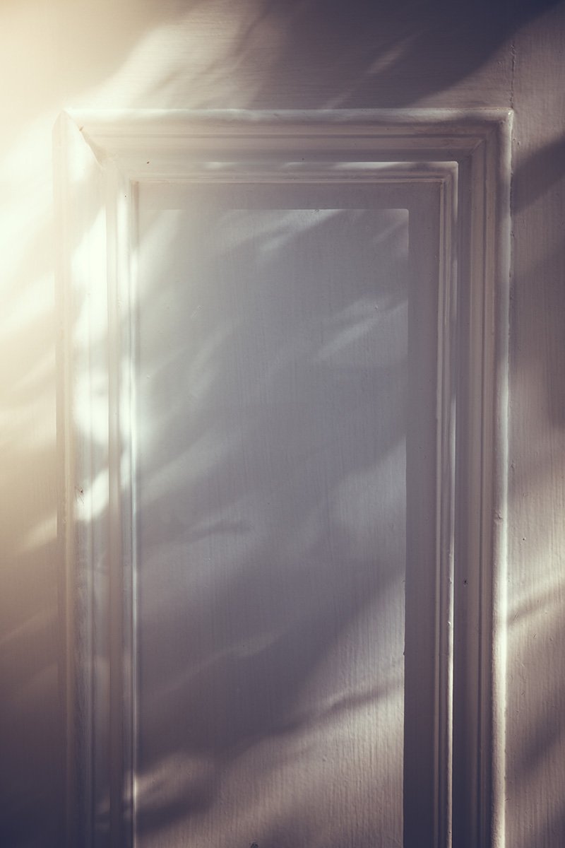 A close-up of a wooden wall panel with light casting shadows on the wall.