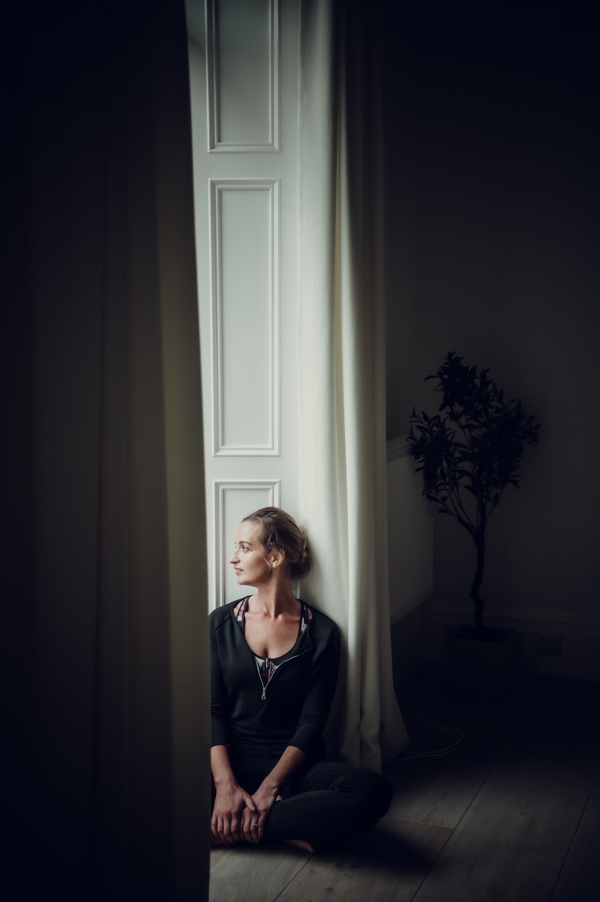 Amy Martin, Tuesday's bride founder, sitting on the floor by a window with textured curtains, illuminated by natural light.