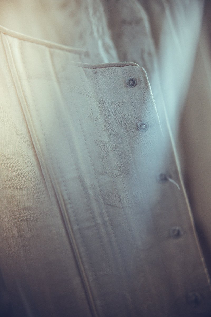 Close-up of a textured, light-coloured bodice with visible stitching and four metal grommets.