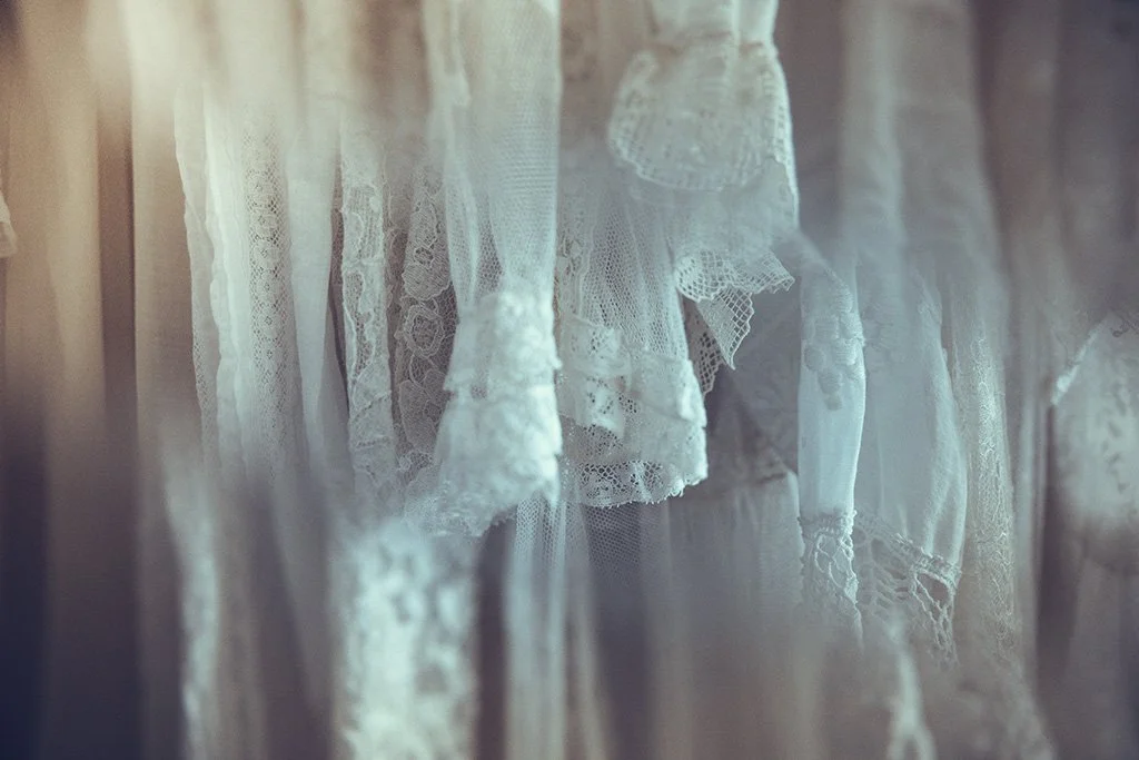 Close-up of Tuesday's bride's vintage lace and embroidered wedding dresses hanging on a rail.