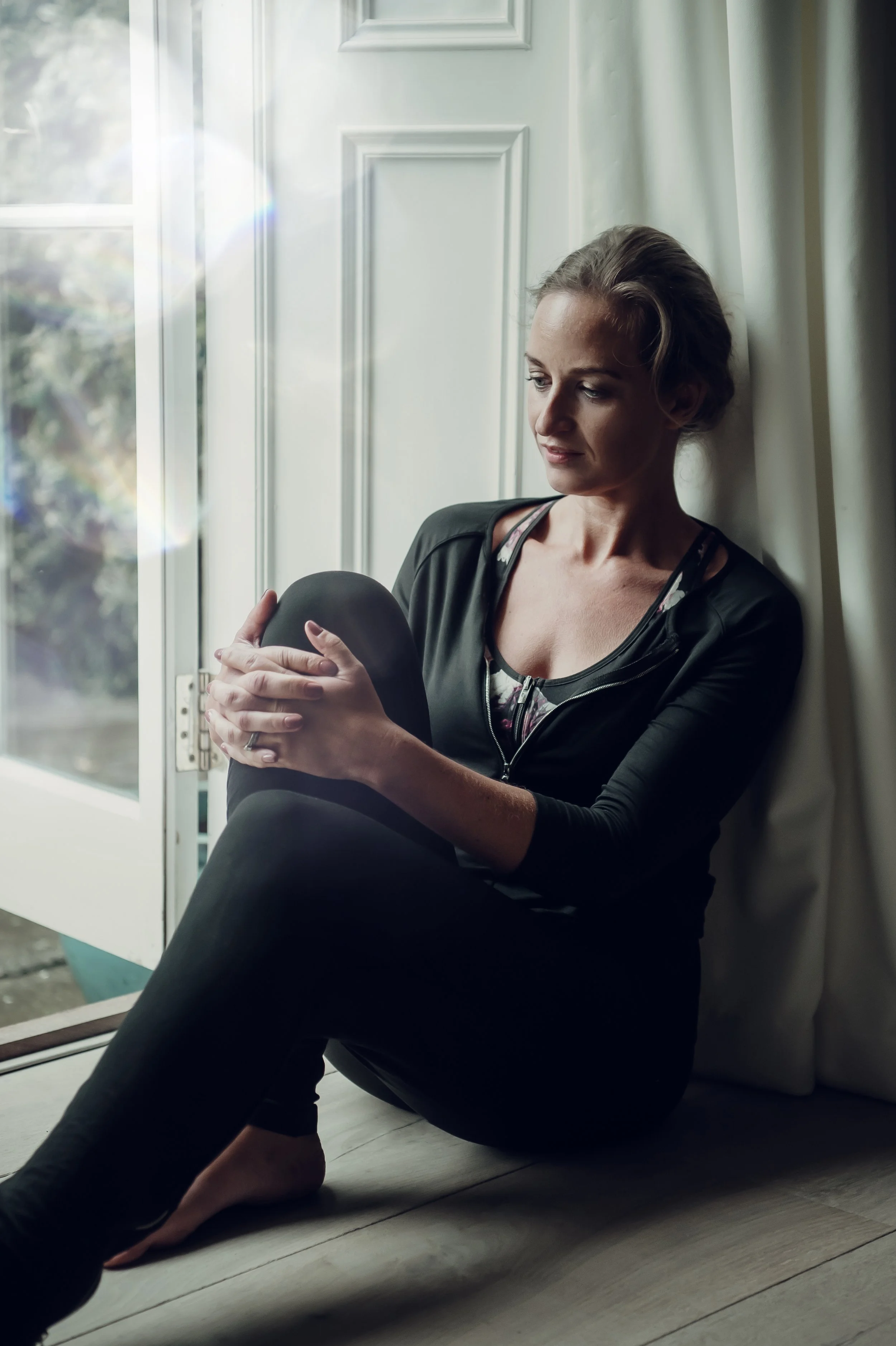 Tuesday's bride founder, Amy Martin, sitting by a window seat, looking outside with her arms around her knee.