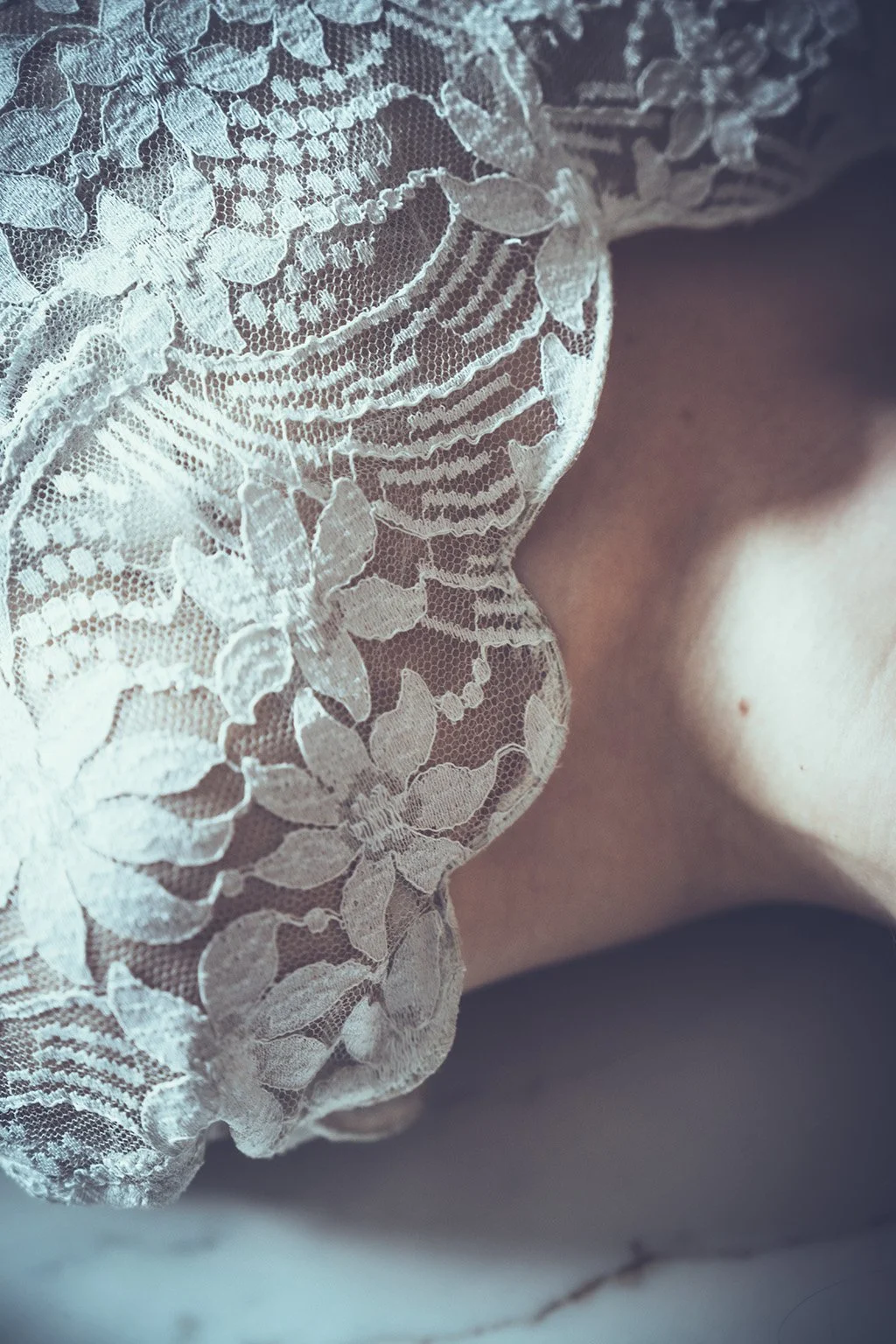 Close-up of white lace sculpted neckline wedding dress with floral patterns.