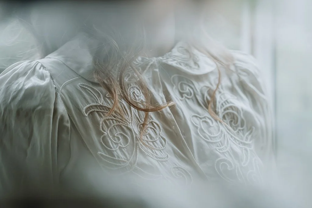 Close-up of a woman's embroidered white wedding dress.