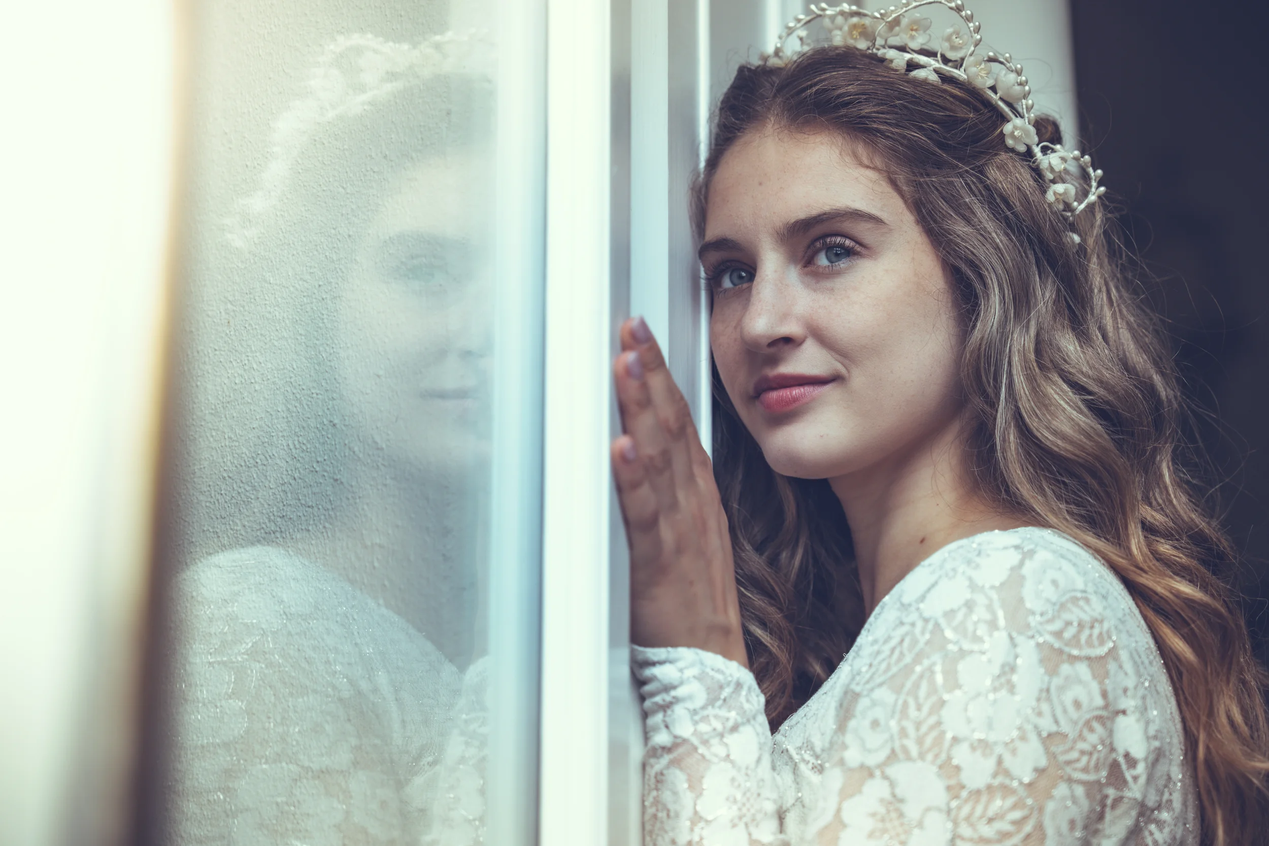 a bride wearing vintage, looking out of a window with reflection