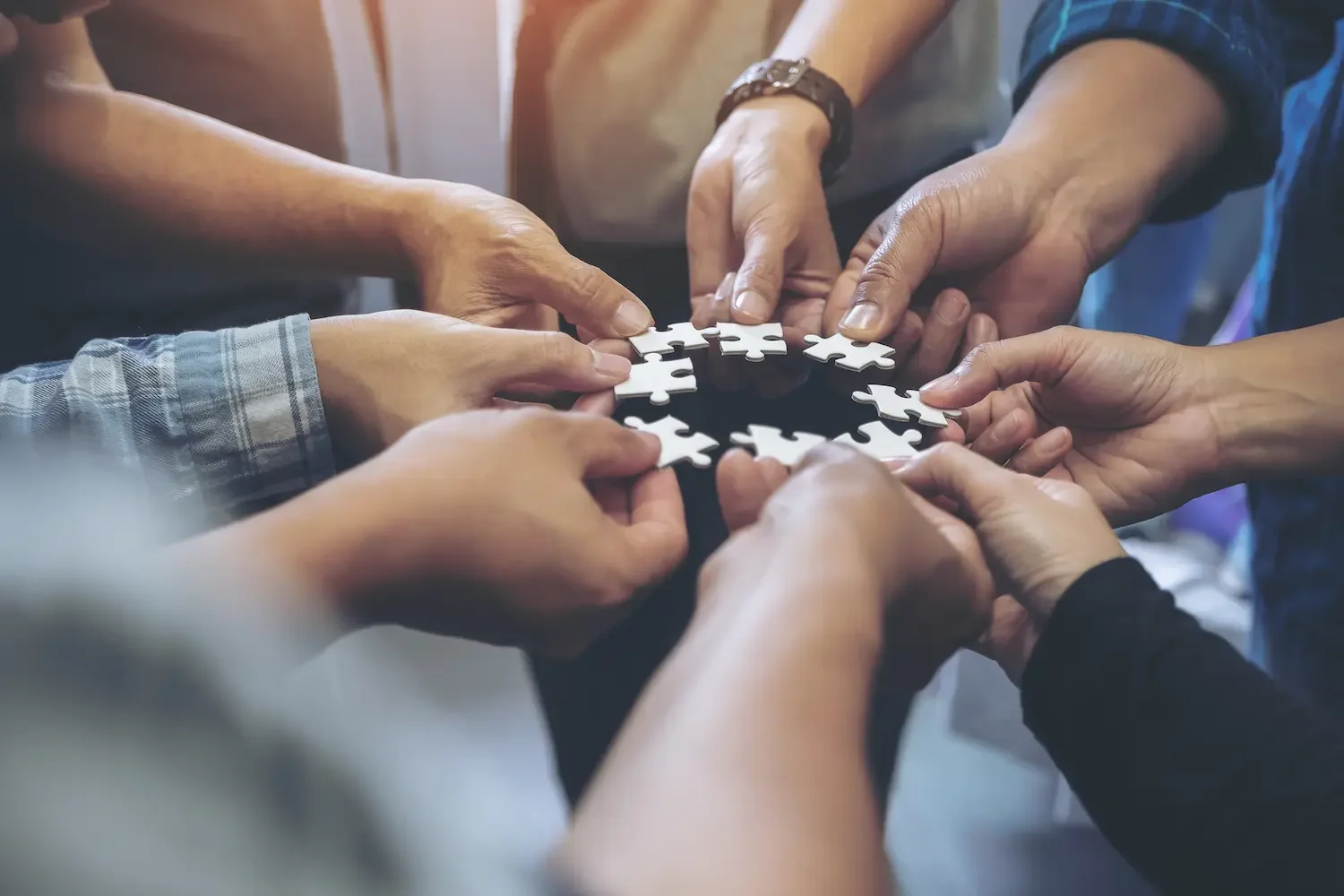 Ein Business Team legt Puzzle-Teile zusammen als Symbol der Gemeinschaft.