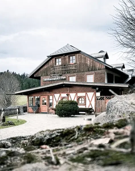 Der Kolmenhof, umgeben von Natur und Bäumen, mit einem Weg im Herbst.