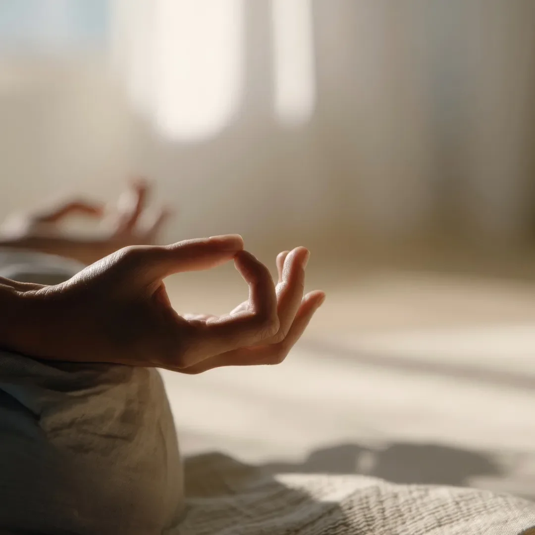 Nahaufnahme einer Hand, die eine Meditation oder Entspannungs-Geste macht, im Sonnenlicht auf den Boden gerichtet.