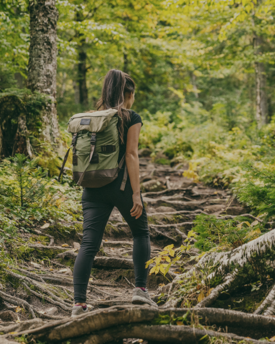 Junge Frau mit Rucksack wandert auf einem Waldboden