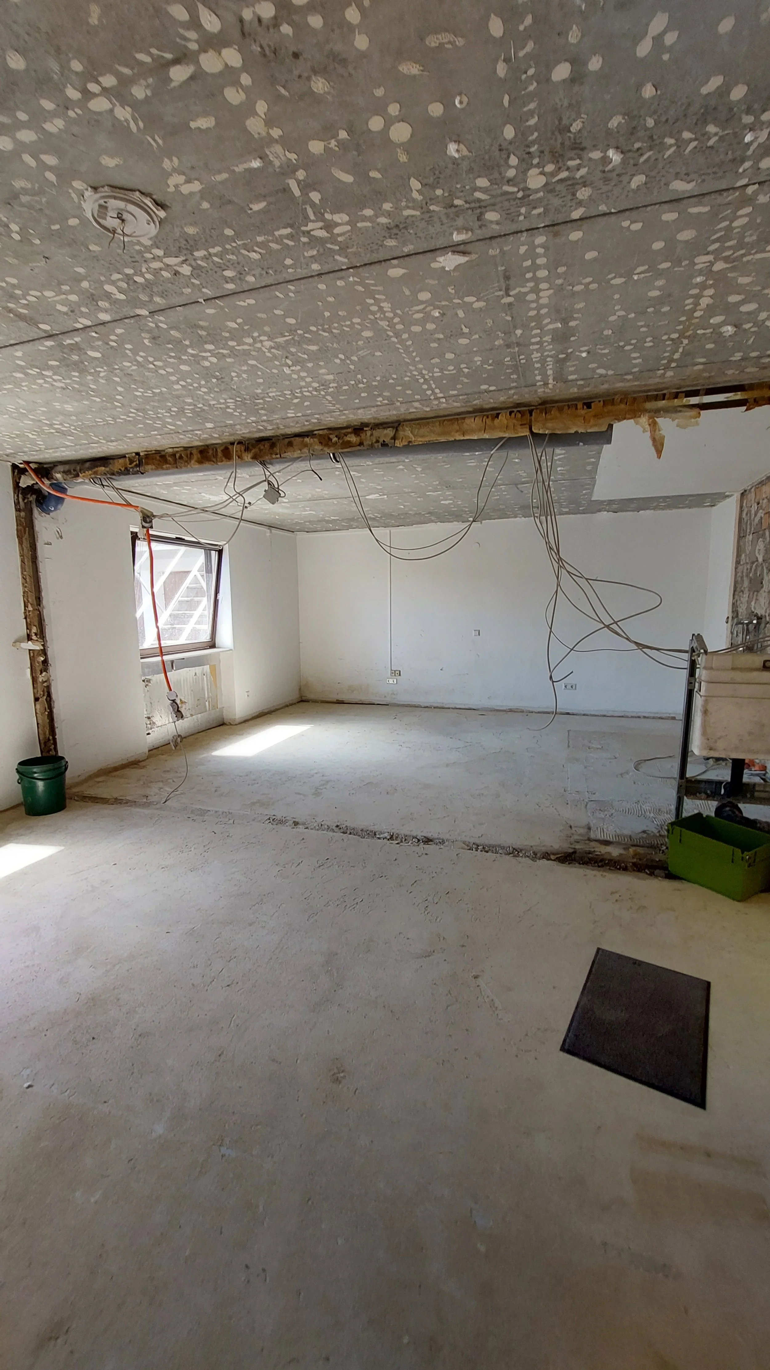 Innenraum des zukünftigen Yoga & Meditationsraum vom Kolmenhof im Bauzustand mit unvollendeter Decke, Kabeln und Fenstern, die noch installiert werden, Boden noch unbefliest.