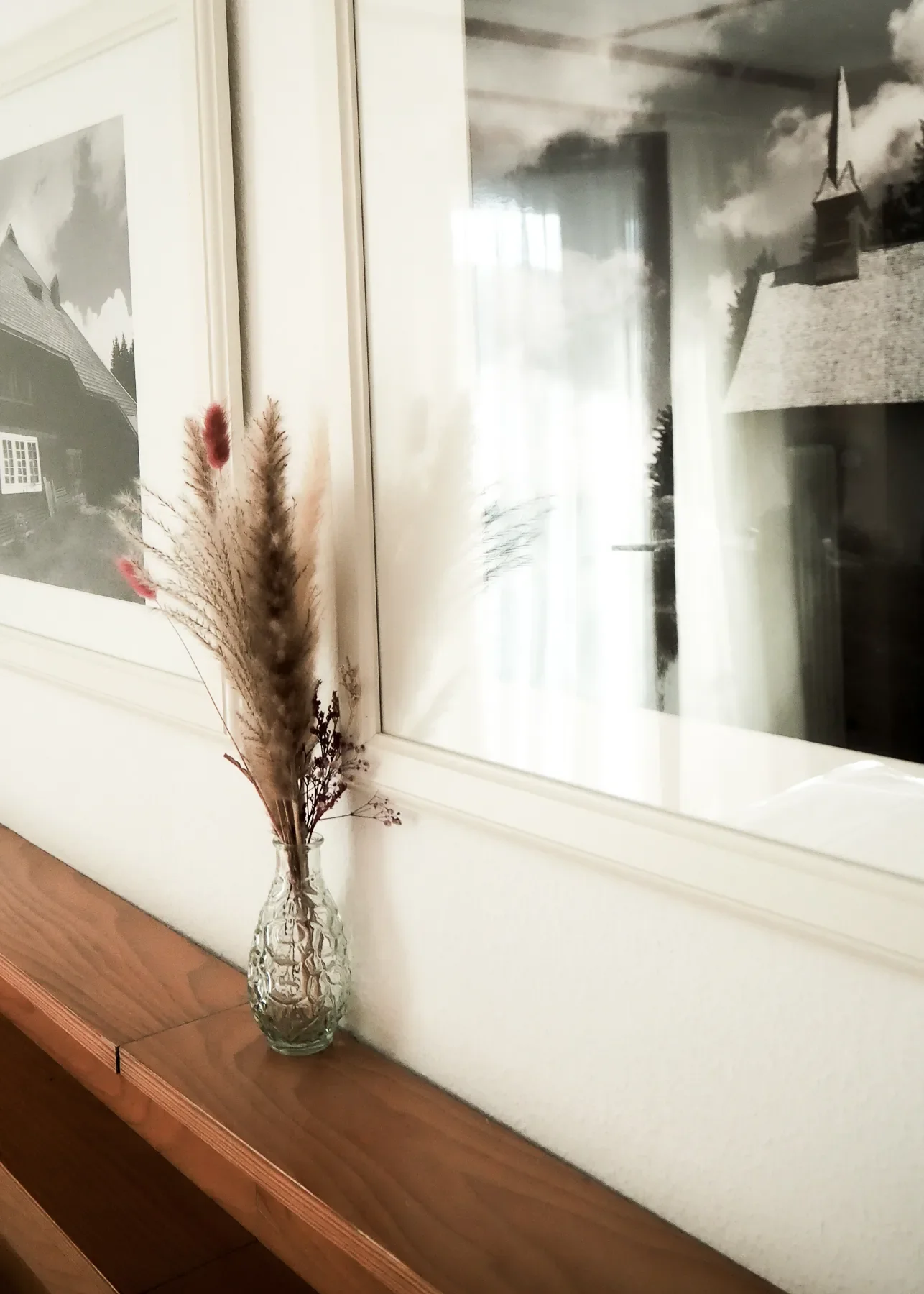 Ein Vase mit Trockenblumen steht auf einer Ablage über dem Bett, in einem Zimmer vom Kolmenhof.