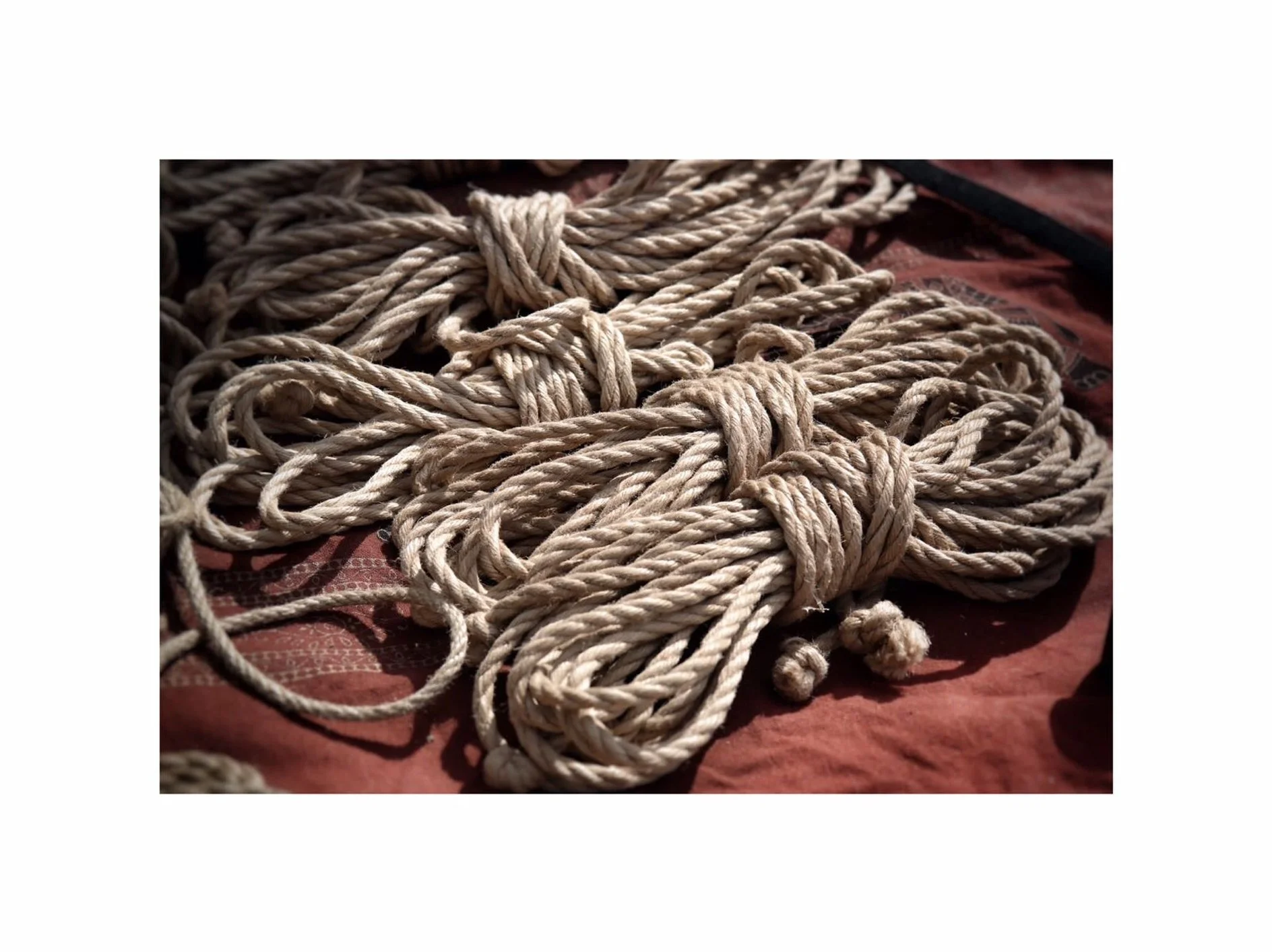 Close-up of tangled, knotted ropes on a reddish fabric surface.