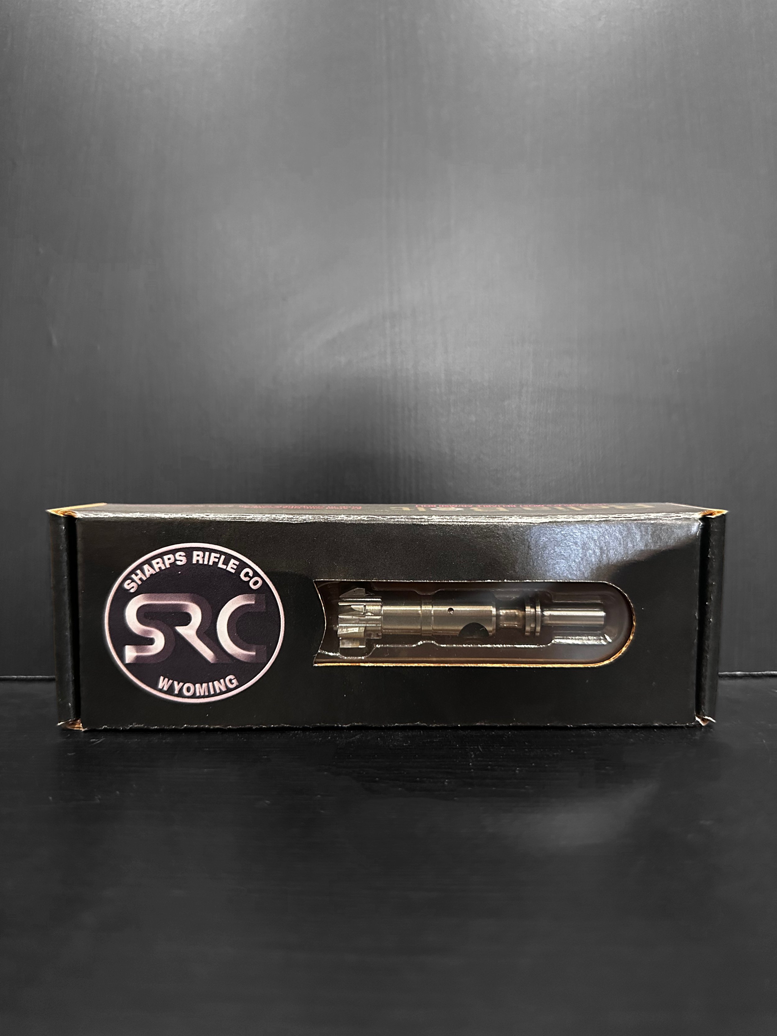 A modern house with wooden and white panel walls, large front window, situated in a mountainous landscape with grassy foreground and steep hills in the background.