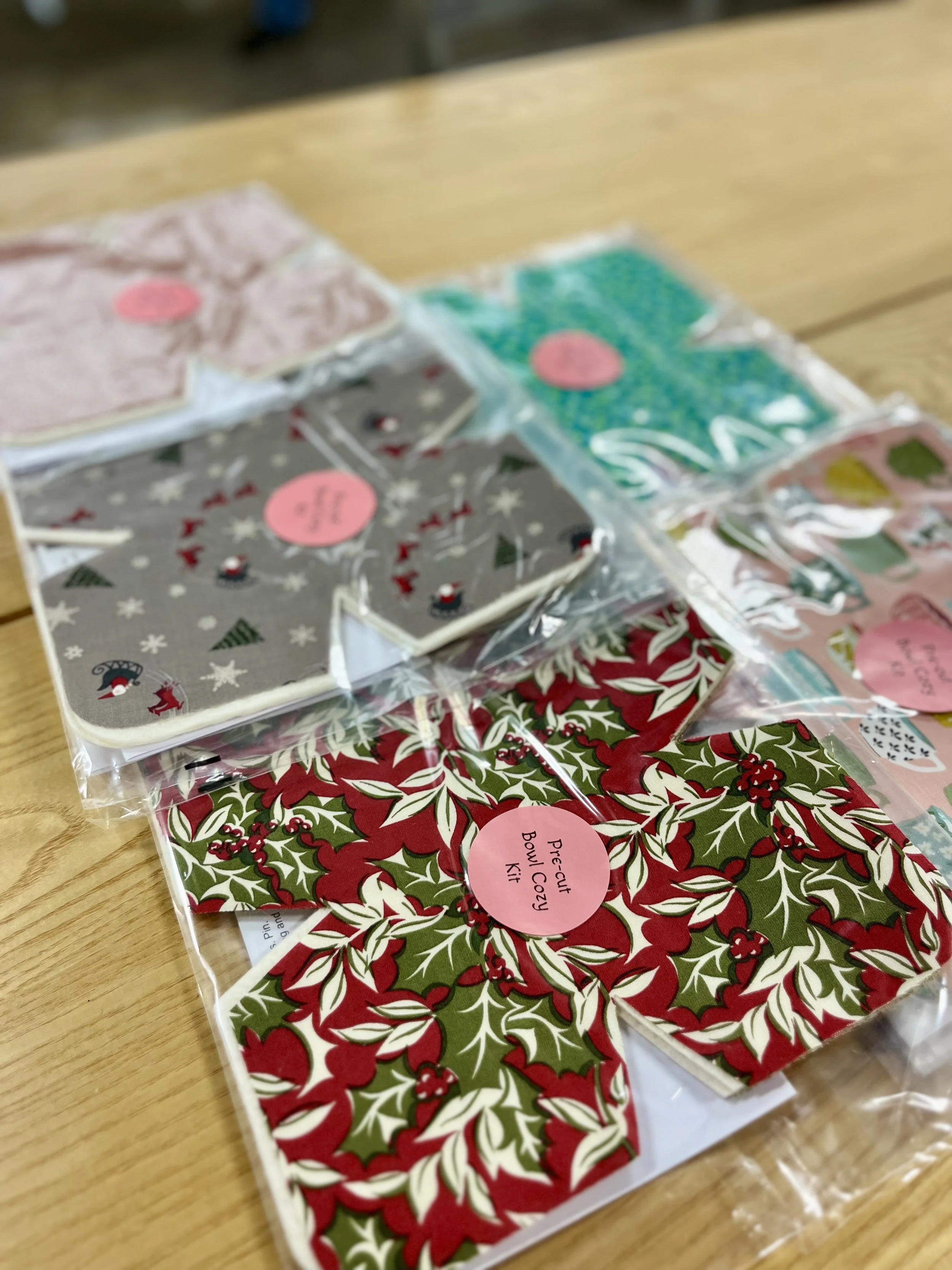 Set of Christmas-themed decorative bow tie kits with holly, snow, and penguin patterns, packaged in clear plastic bags on a wooden surface.