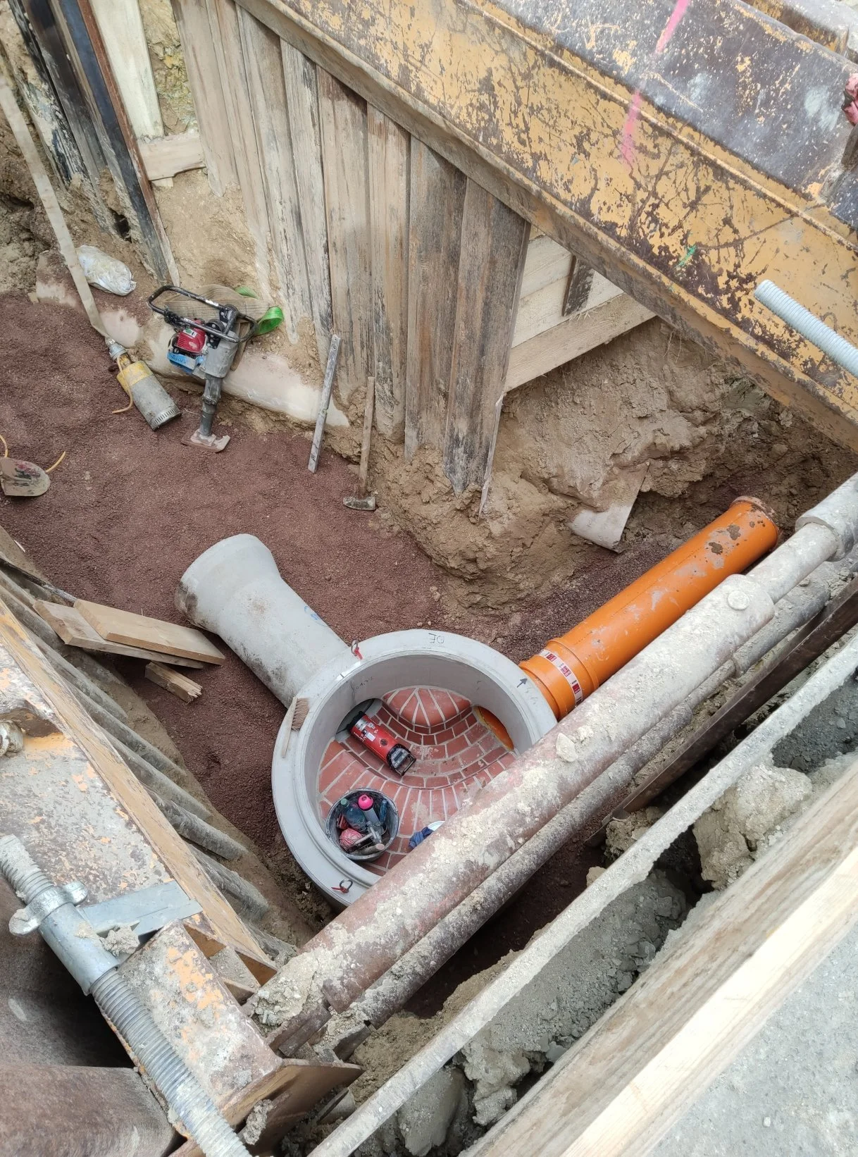 Baustelle mit Rohrleitungssystem, Tauchpumpe, Werkzeugen und Holzrahmen im Erdgeschoss. Es findet eine Installation im Erdgeschoss statt.