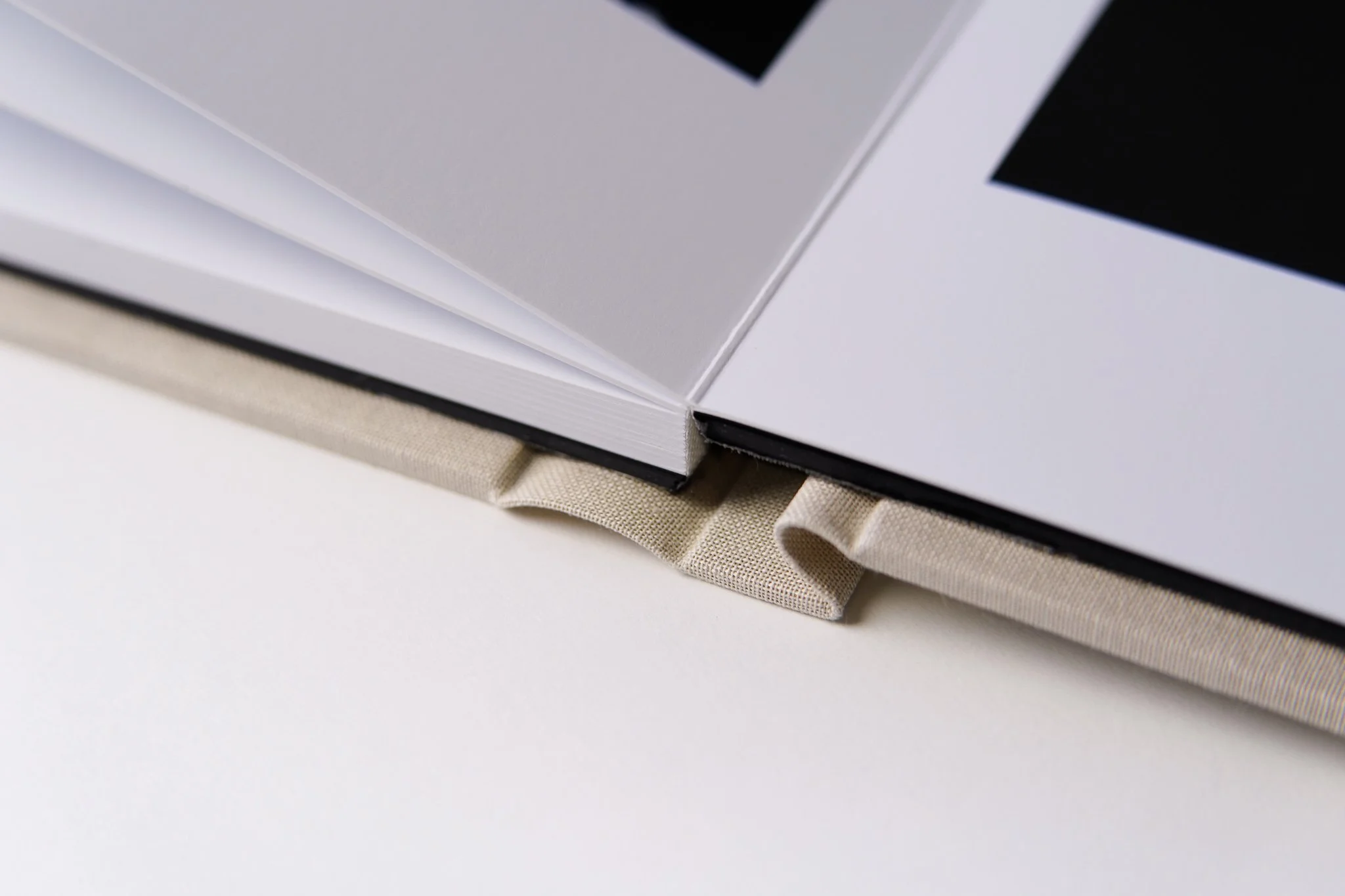 Close-up of an open book resting on a beige fabric-covered surface.