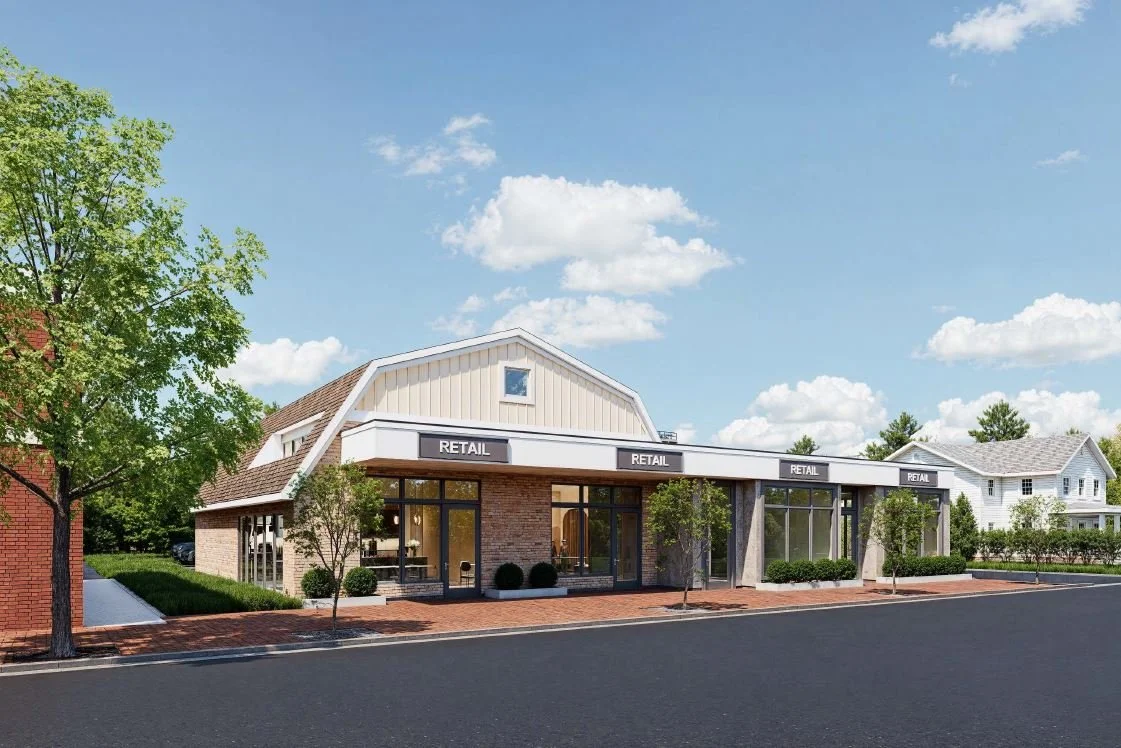A modern retail shopping center with large glass windows, brick and siding exterior, and multiple entrances, situated along a paved street with trees and a clear blue sky.