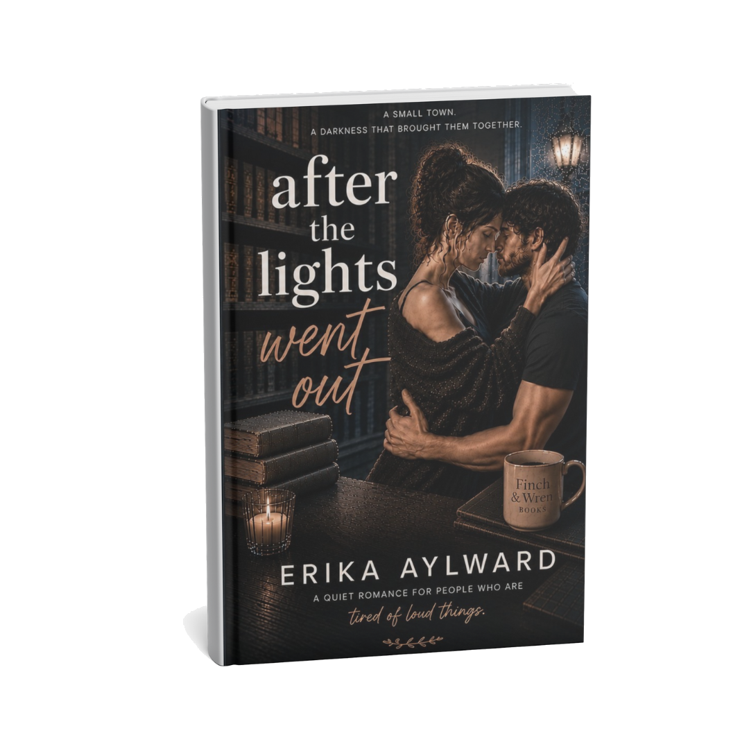 Cover of a romance novel titled 'after the lights went out' showing a man and woman embracing in a dimly lit library with books, a lit candle, and a coffee mug.