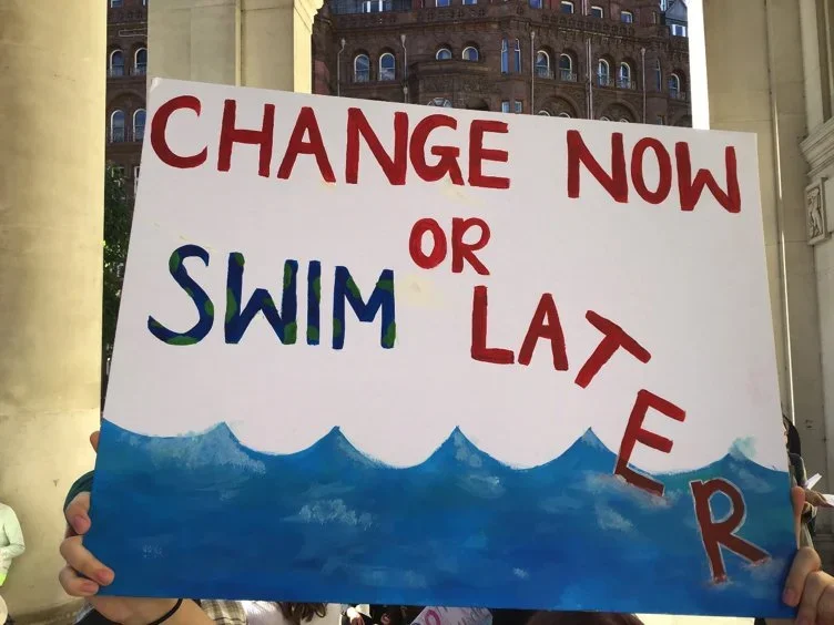 Hand painted sign that reads 'change now or swim later'