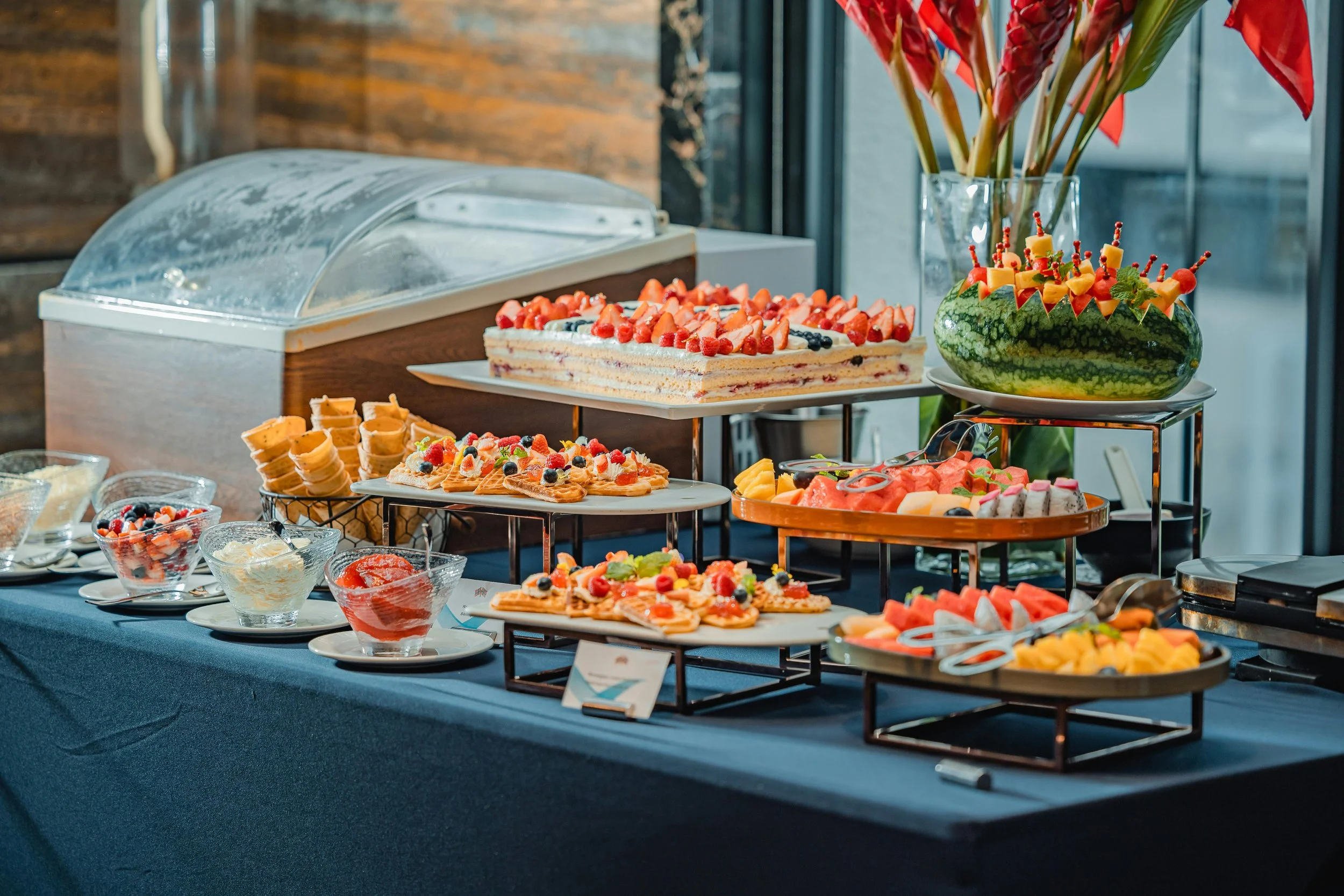 Dessert buffet with cakes, fruit, and pastries on a black tablecloth.