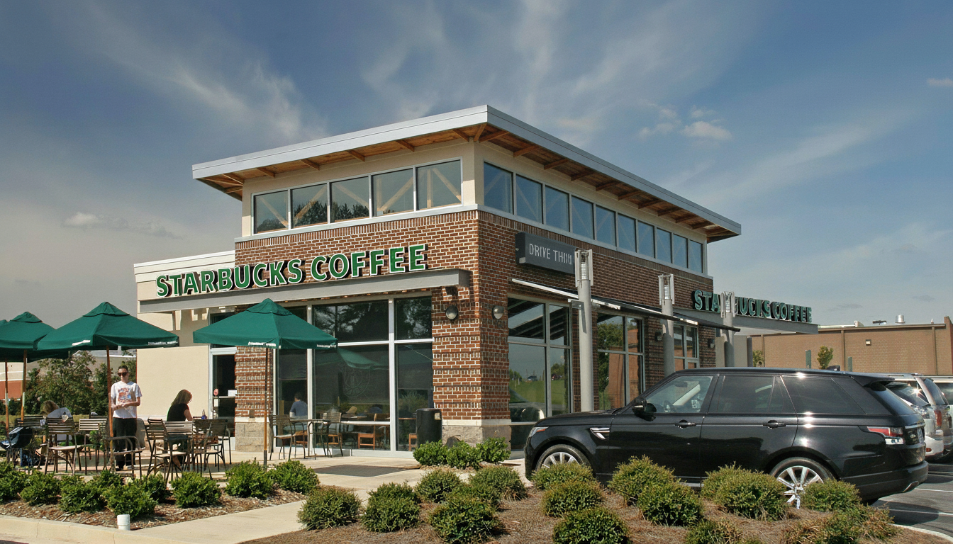 Starbucks Coffee storefront with outdoor seating, parked cars, and customers outside on a sunny day.
