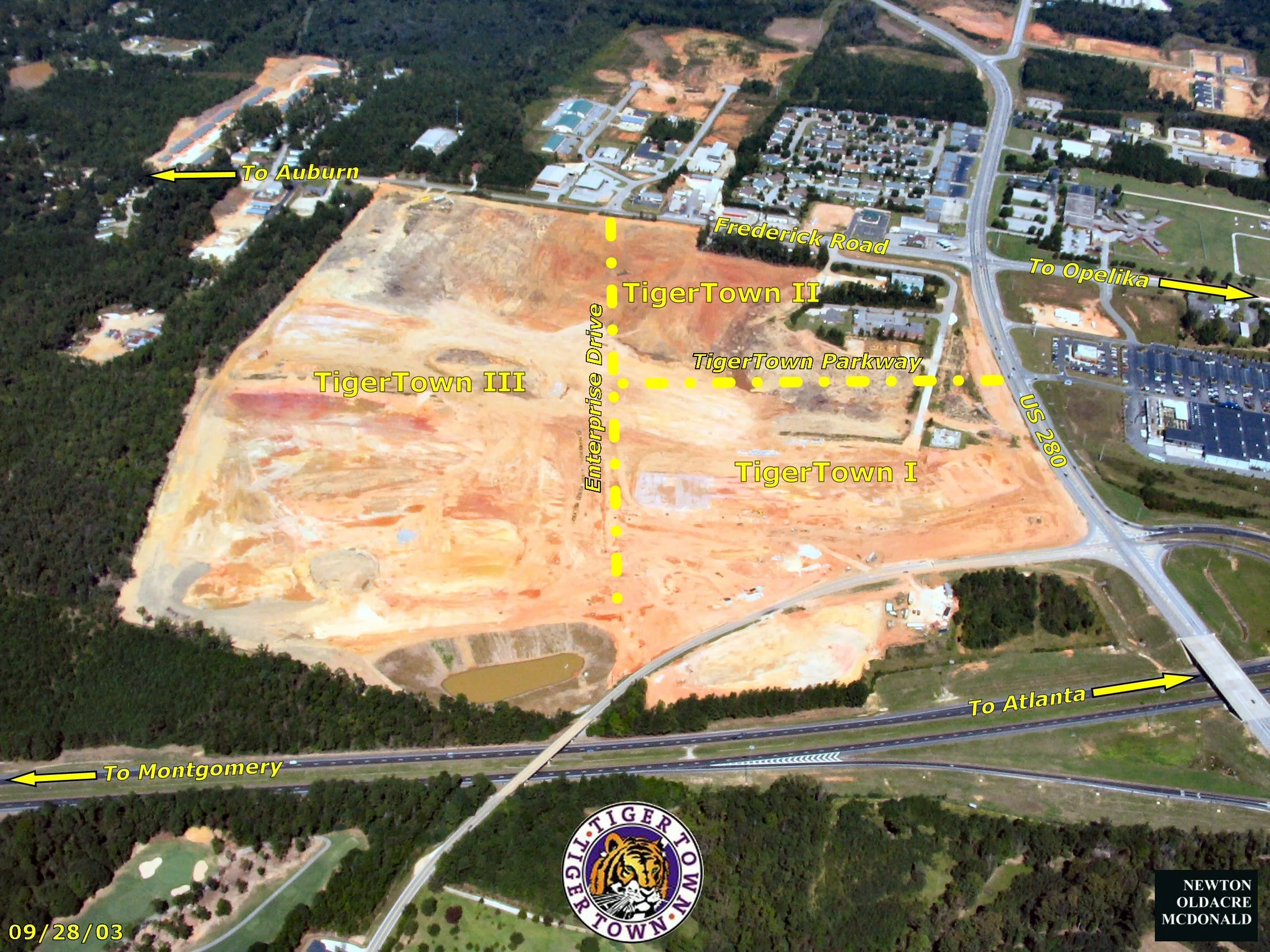 Aerial view of TigerTown area with labeled roads and subdivisions. Labels include 'To Auburn,' 'To Opelika,' 'To Montgomery,' and 'To Atlanta.' Other labels are 'TigerTown II,' 'TigerTown III,' 'TigerTown I,' with colored dotted lines marking different areas. The image also features a circular TigerTown logo at the bottom, date in bottom left corner.