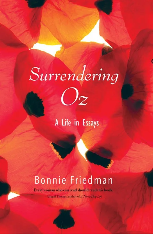 Book cover for 'Surrendering Oz: A Life in Essays' by Bonnie Friedman, featuring overlapping red and orange poppy petals with black centers.
