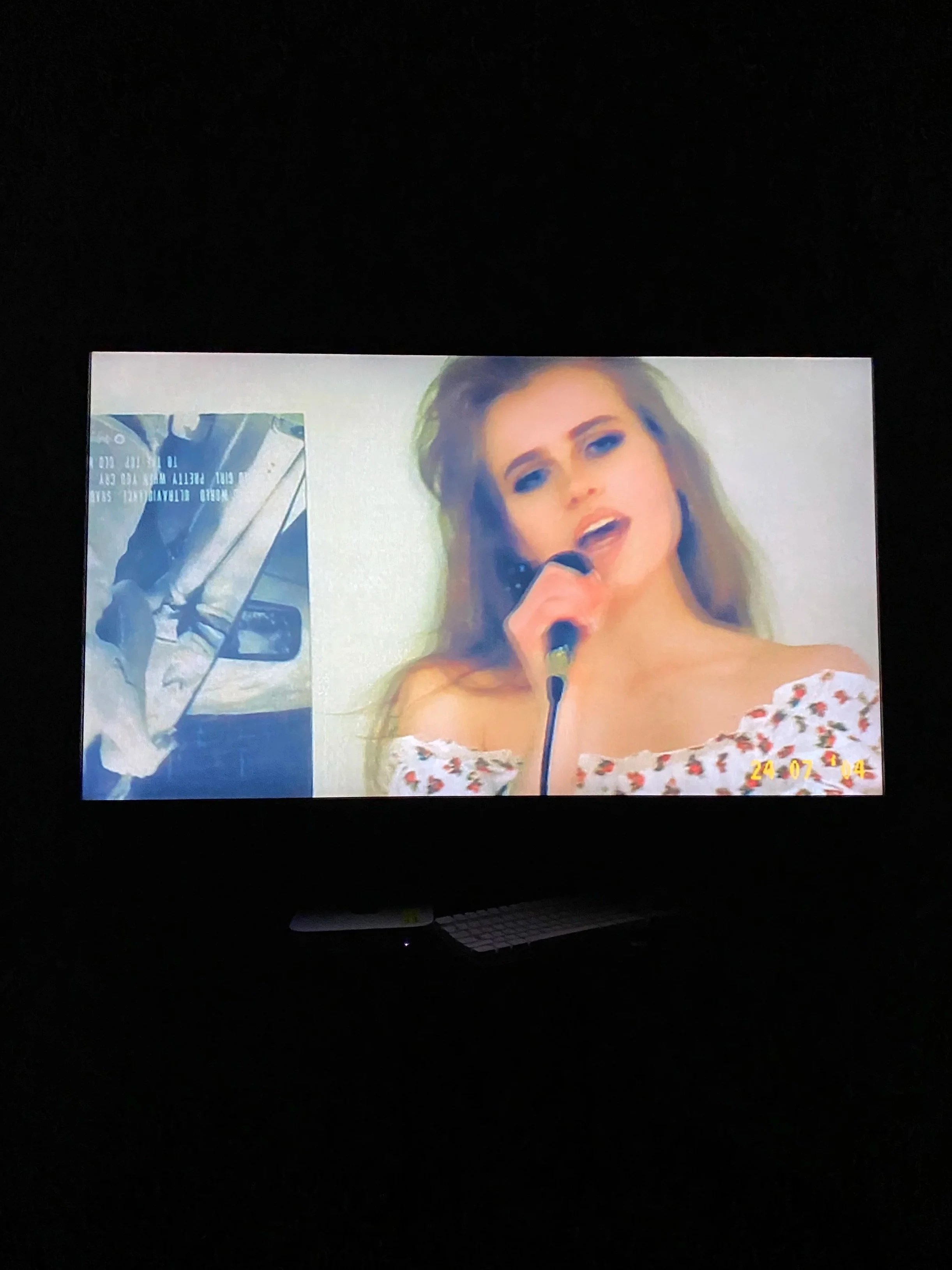 A woman singing into a microphone on a television screen, with a date stamp of July 24, 2004 in the bottom right corner.