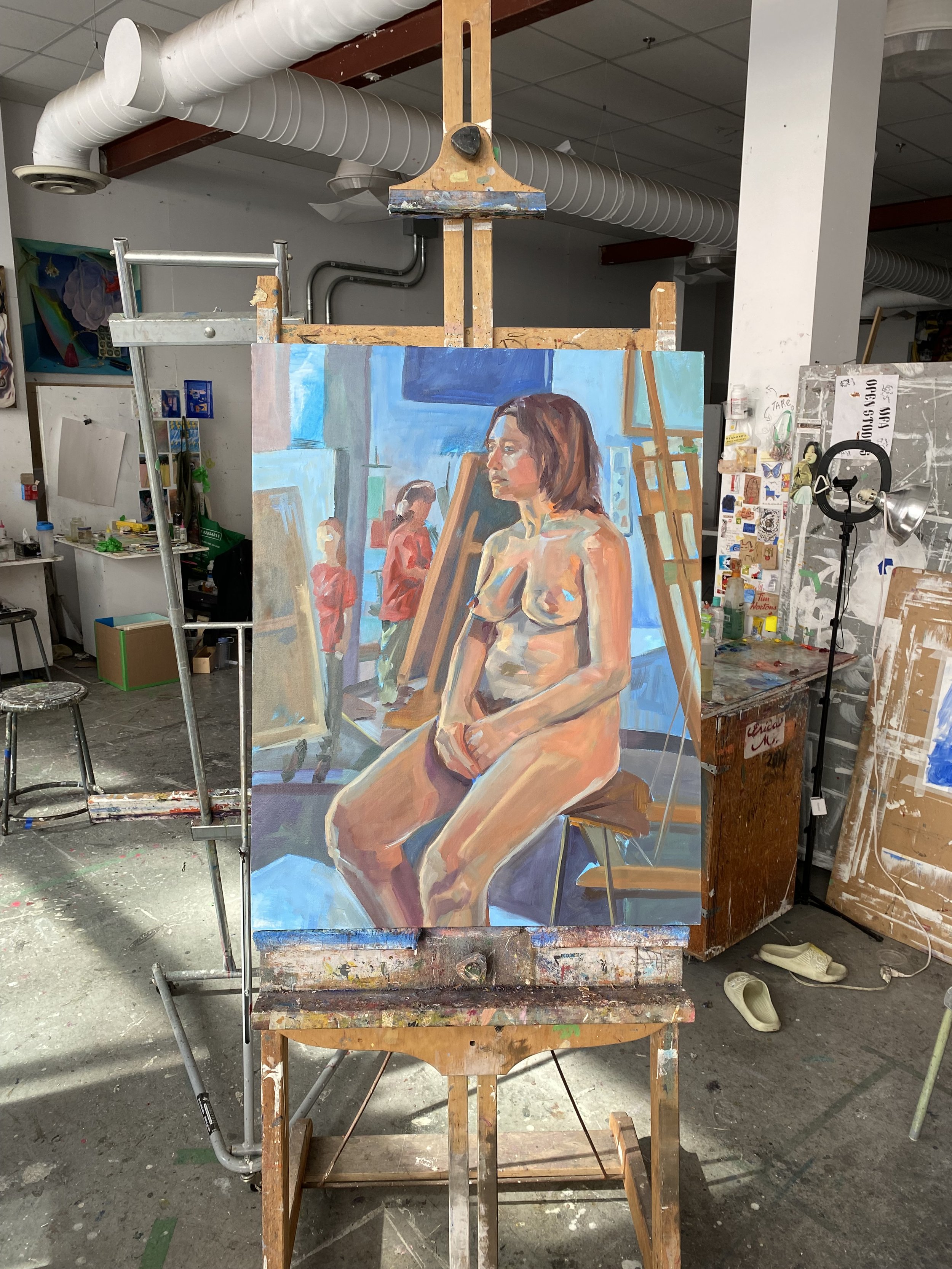 A painting of a nude woman sitting on a stool in an art studio, with an easel and two figures in red jackets in the background.