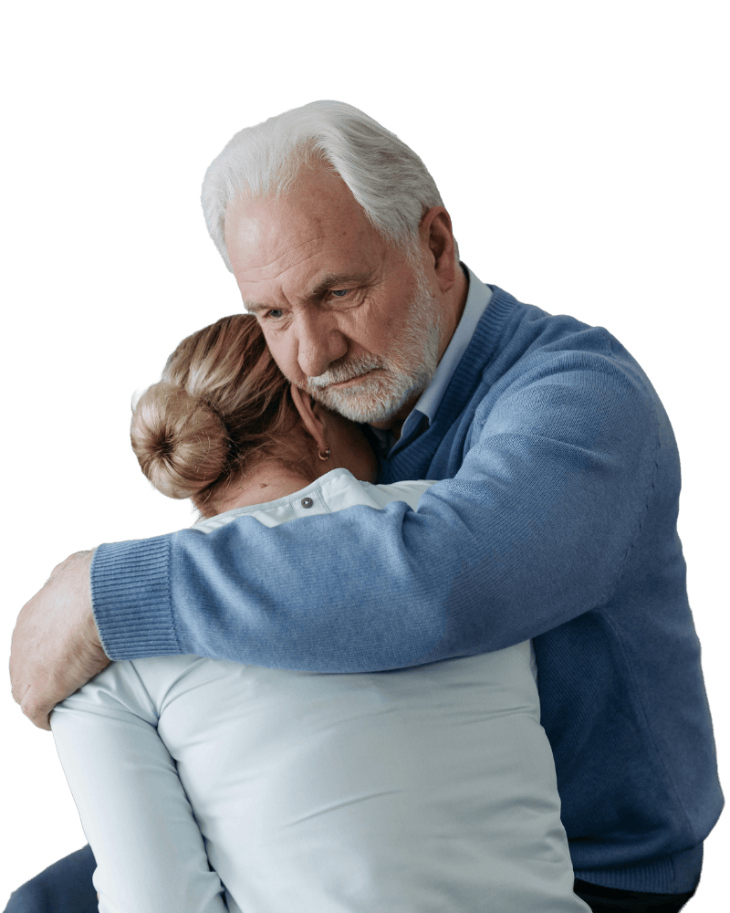 Een oudere man omhelst een vrouw liefdevol en troostend, beiden hebben een emotioneel moment.