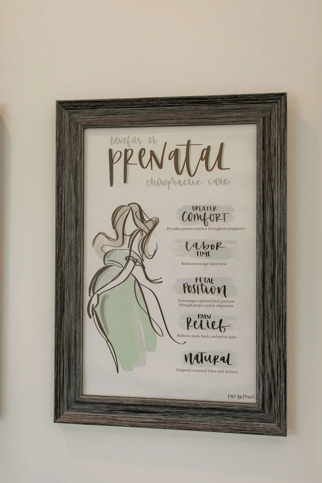 A framed poster titled "Benefits of prenatal chiropractic care" listing benefits such as greater comfort, labor time, fetal position, pain relief, and natural birth, with a line drawing of a pregnant woman.