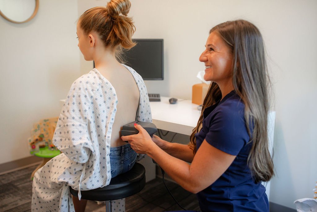 A healthcare professional using an ultrasound device on a young girl during a medical exam in a clinic