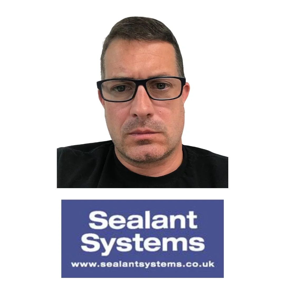 A man with short dark hair, wearing black glasses and a black shirt, looking directly at the camera. Below him is a blue rectangular sign with white text that reads 'Sealant Systems' and a website URL 'www.sealantsystems.co.uk'.