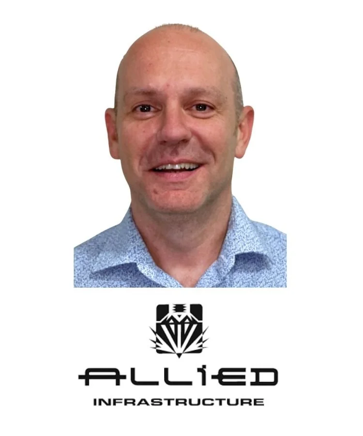 A smiling man in a blue shirt with a bald head, photo is above a logo that says "ALLIED INFRASTRUCTURE" with a geometric design.