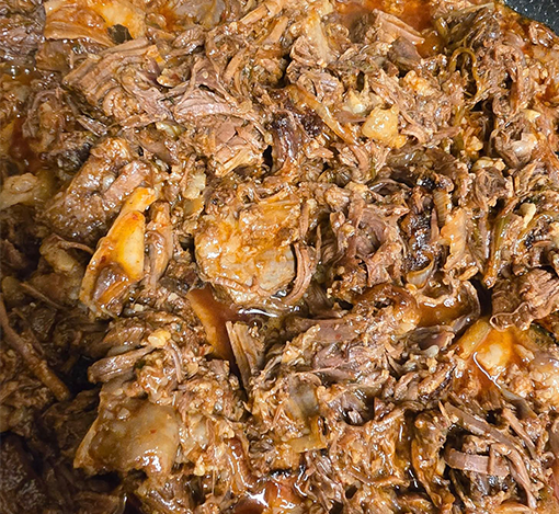 Close-up of shredded cooked beef with sauce.