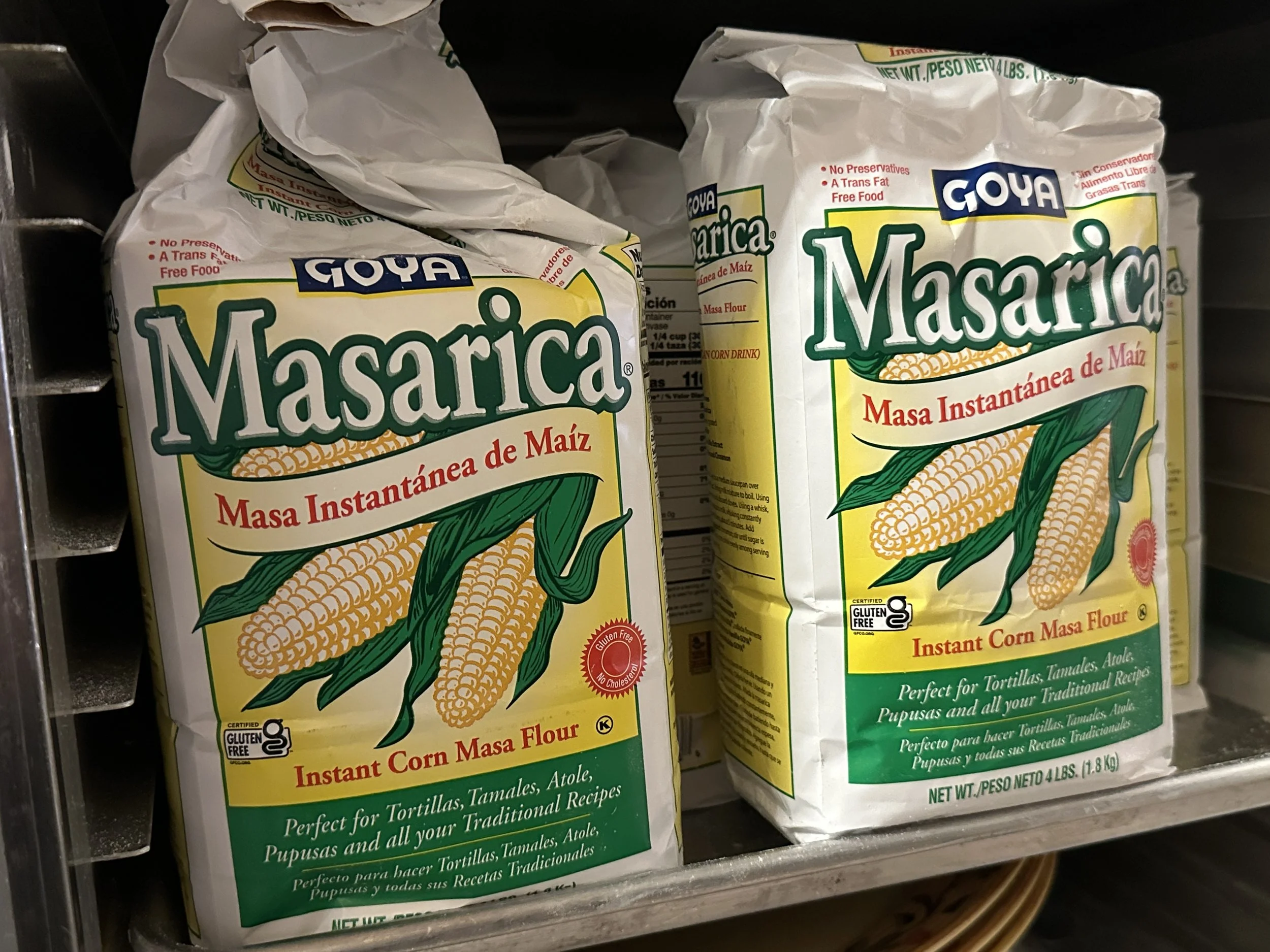 Two packages of Goya Masarica instant corn masa flour on store shelf.
