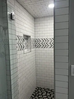 Modern walk-in shower with white subway tile, black & white chevron accent band and built-in niche – Harrisville, Utah basement remodel by VCON Remodeling & Restoration