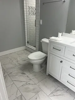 Fully remodeled basement bathroom featuring marble-look porcelain tile, white shaker vanity and modern fixtures – Harrisville, Utah by VCON Remodeling & Restoration