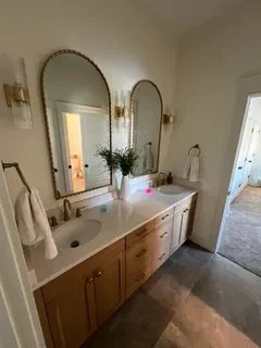 After: Luxurious bathroom with wood double vanity, arched gold-framed mirrors and modern lighting – Ogden, Utah remodel by VCON Remodeling & Restoration