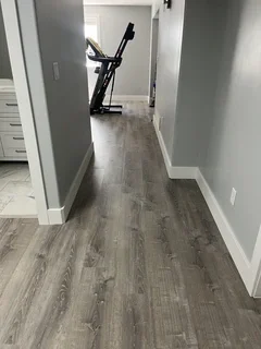 Open basement hallway with continuous luxury vinyl plank flooring leading to home gym area – Harrisville, UT remodel by VCON Remodeling & Restoration