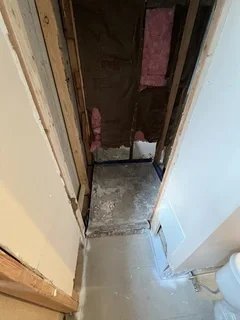 Before: Flooded and water-damaged basement bathroom showing torn-out drywall and old plumbing – Clearfield, UT restoration project by VCON