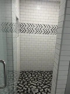After: walk-in shower with black & white pebble floor, subway tile walls and geometric chevron accent – Harrisville, Utah basement finish by VCON