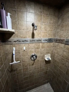 Before: Dated basement shower with original fixtures, fish tile border, and handheld sprayer – Harrisville, UT before modern bathroom rebuild by VCON