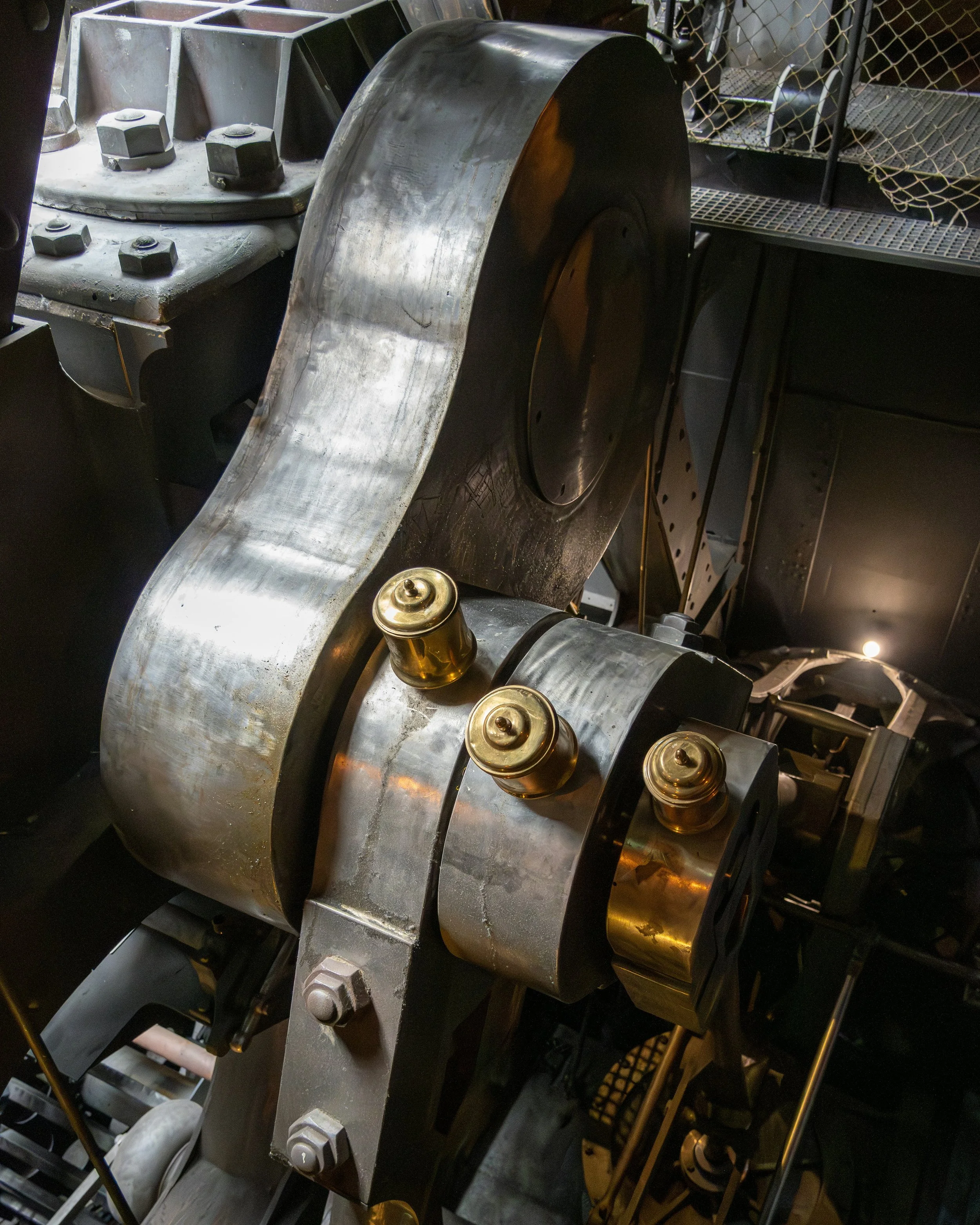 Nahaufnahme eines großen Maschinenteils aus Metall mit Bolzen und mechanischen Komponenten in einer Industrieumgebung.