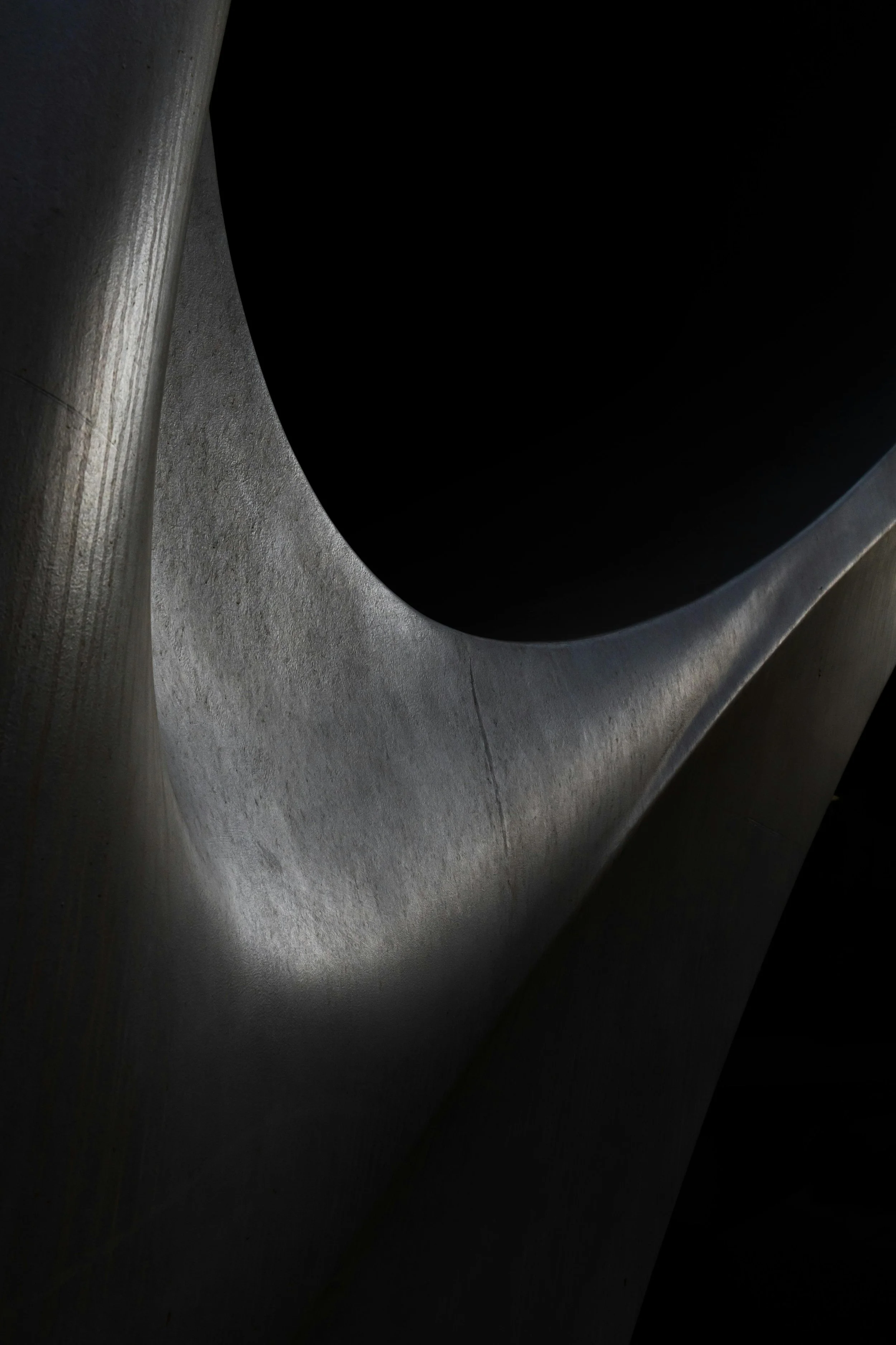 Ein fotografiertes Blick auf eine moderne, curved Metallstruktur mit dunklem Hohlraum.