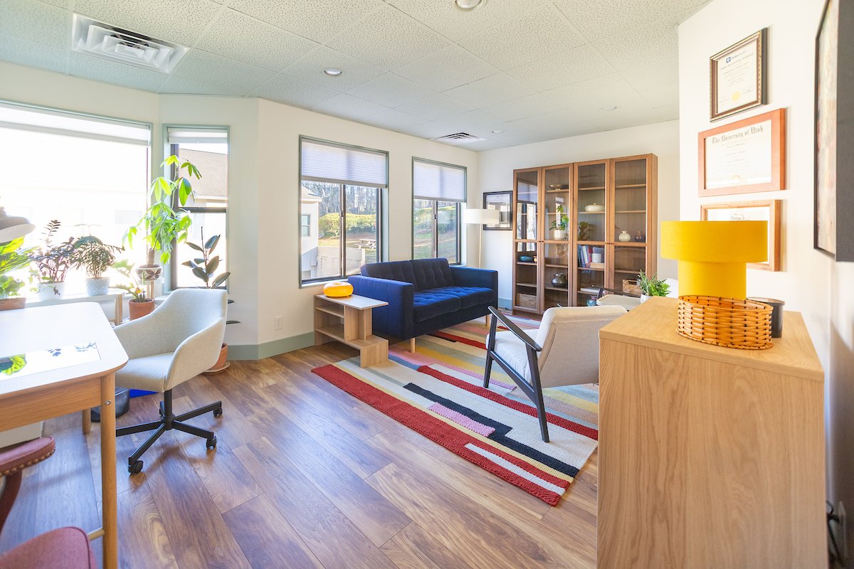 A psychiatrist office with a blue couch and colorful rug
