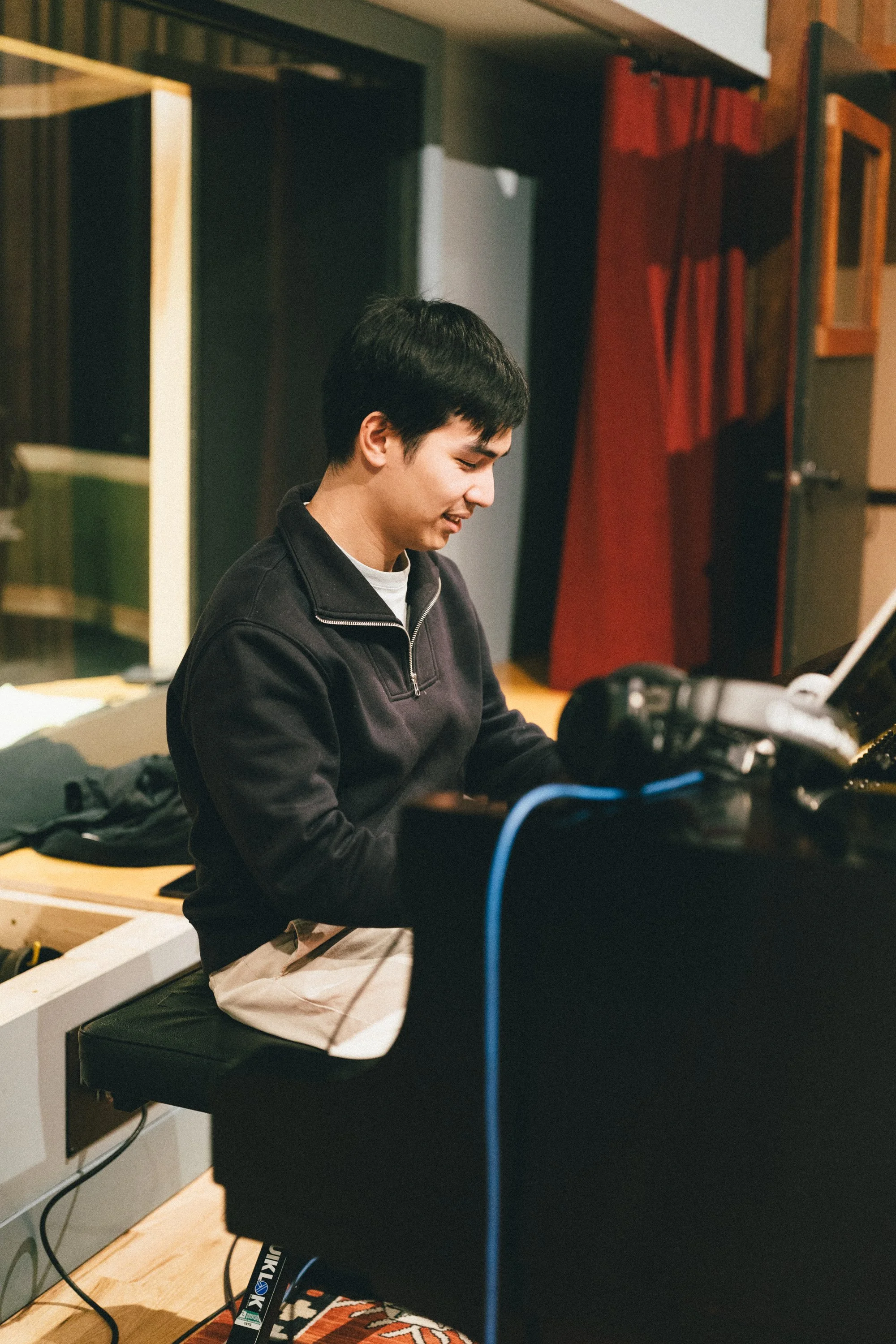 A young man playing the piano in a music studio or practice space.
