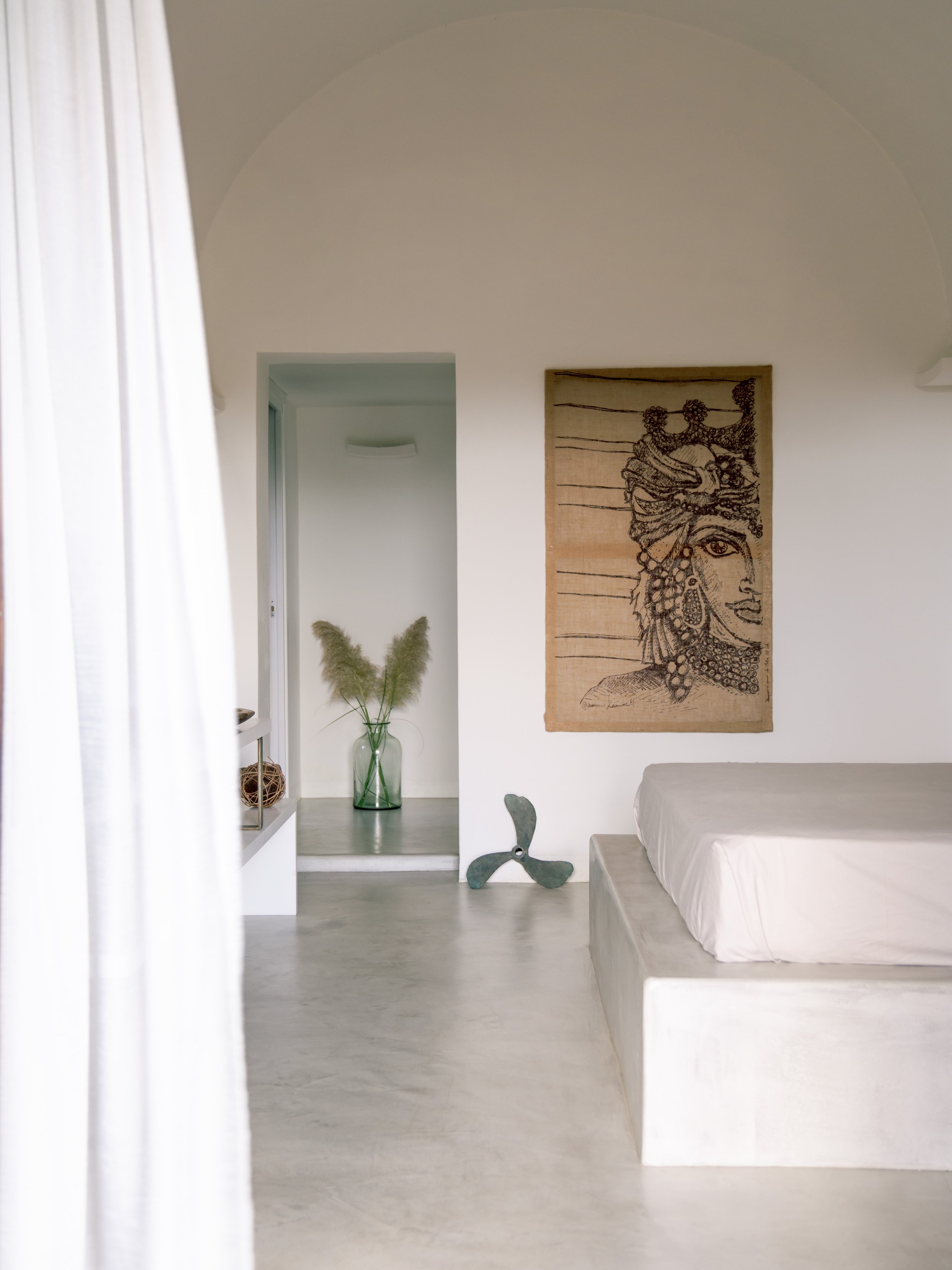 Interno di una stanza minimalista con pareti bianche, un quadro con una testa di moro.