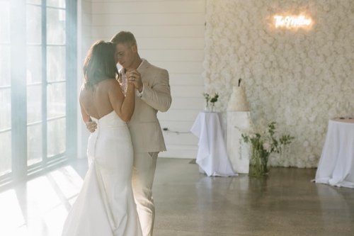 A couple dancing closely during their wedding reception in a bright, decorated indoor venue.